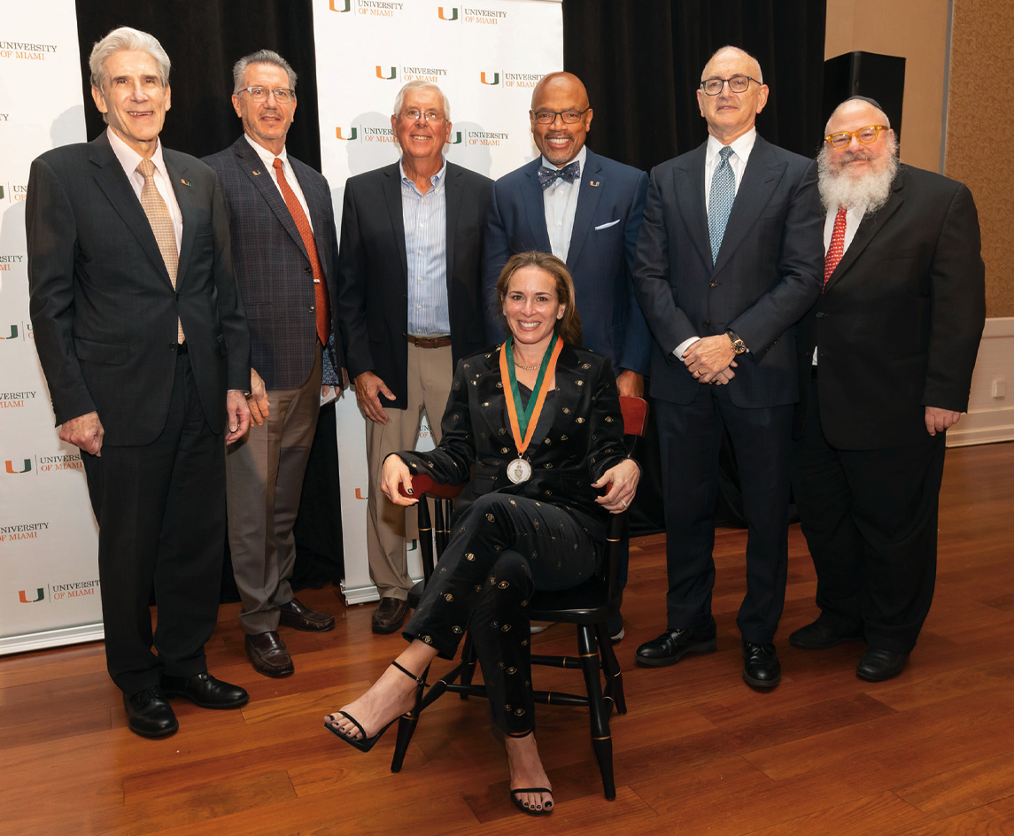 Photograph of Erin Kobetz, Ph.D., M.P.H., (sitting) winner of John K. and Judy H. Schulte Senior Endowed Chair in Cancer Research with  her team members who are standing around her.