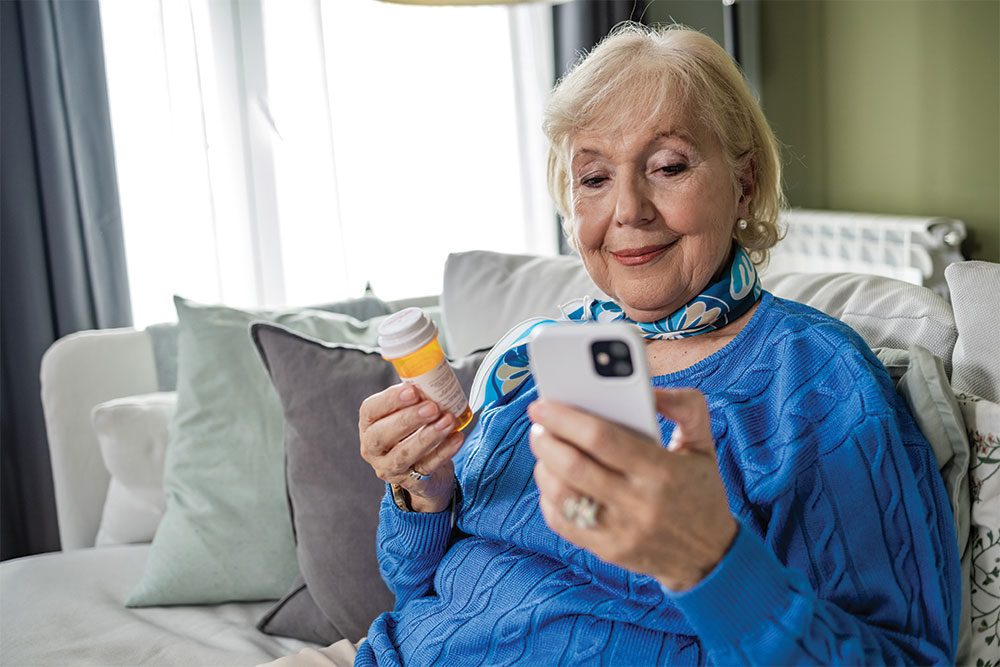 older lady holding medication in one hand and a cell phone in her other hand