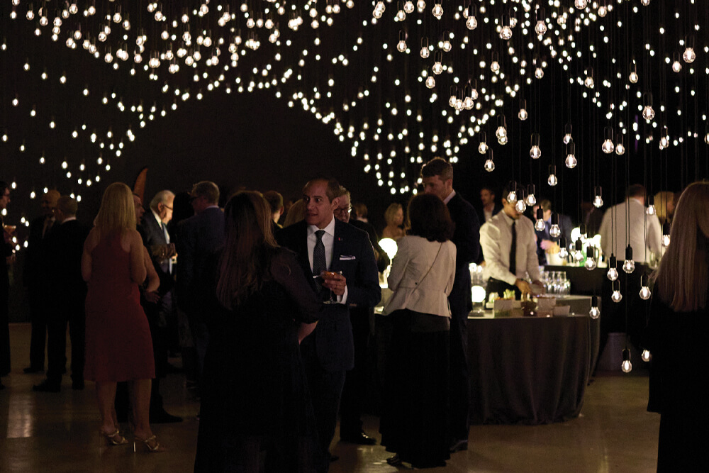 People standing at an event underneath white decorative ligths