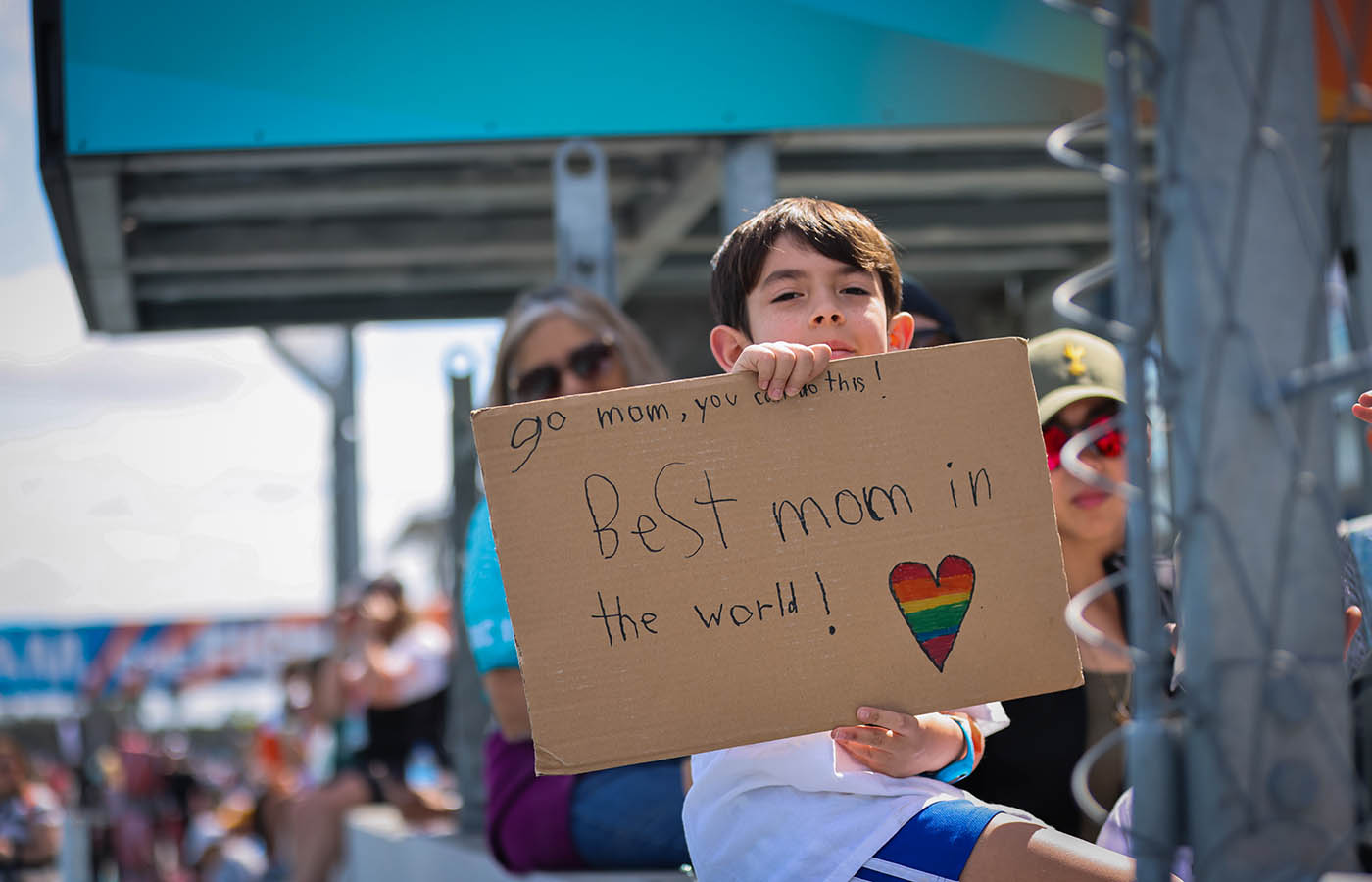 Child holding up a sign highlighting mothers fight with cancer