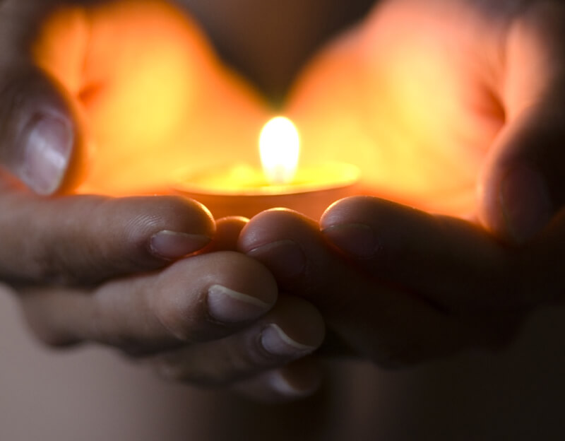 Two hands holding a candle