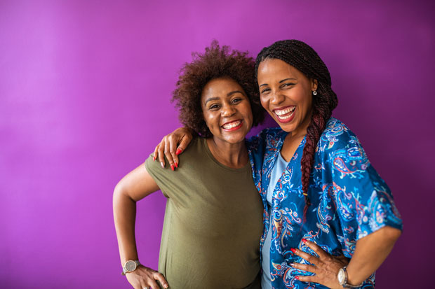 Two women standing in front of a purple backdrop