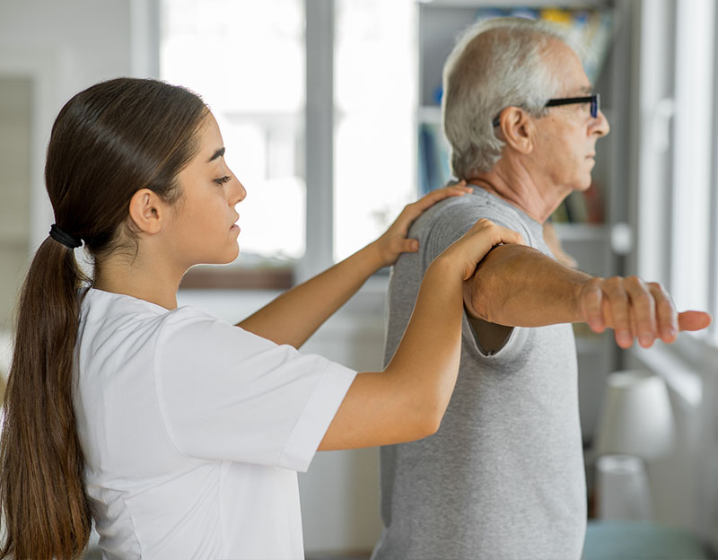 Woman giving an older man physical therapy