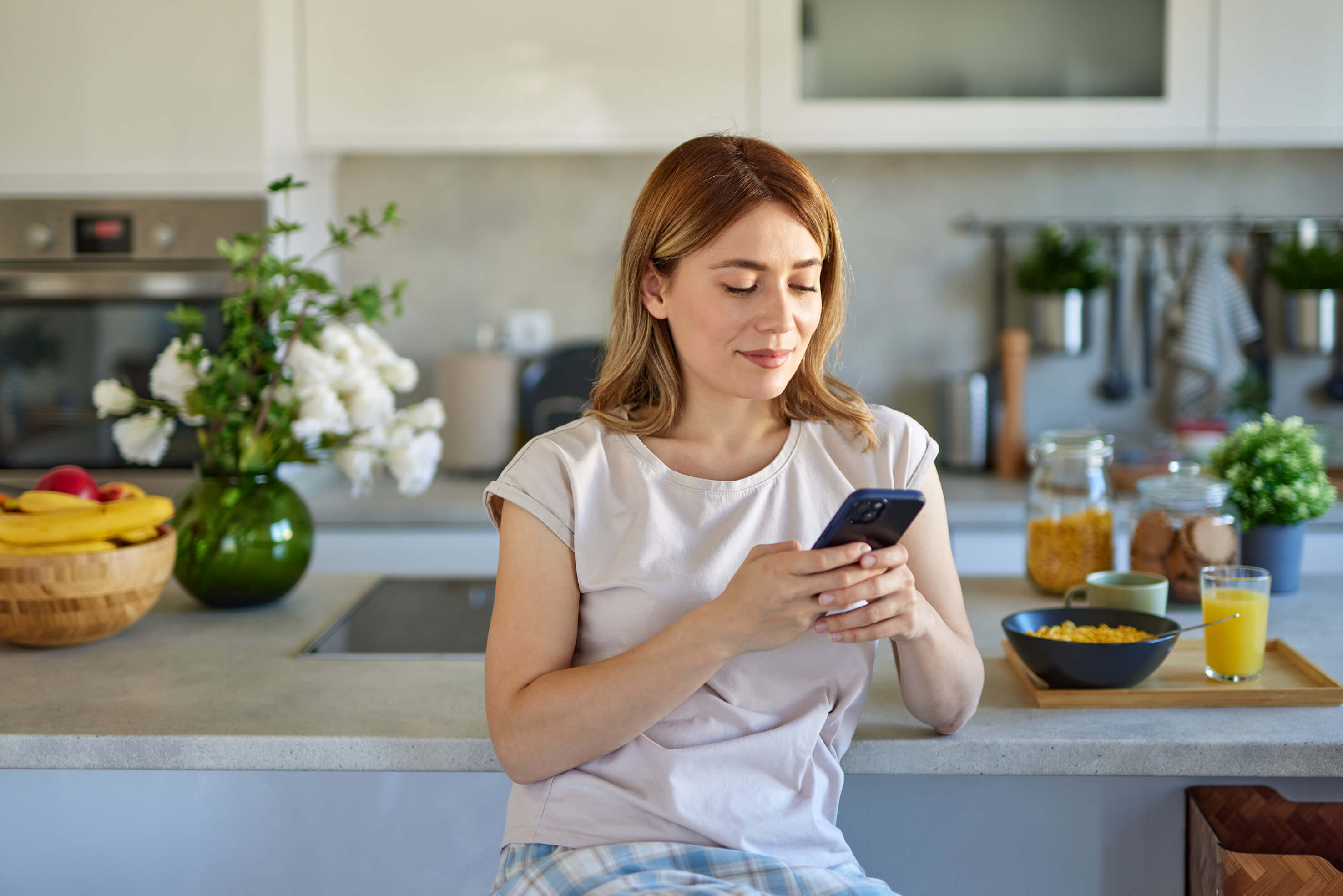 Woman looking at her phone sitting in her kitchen