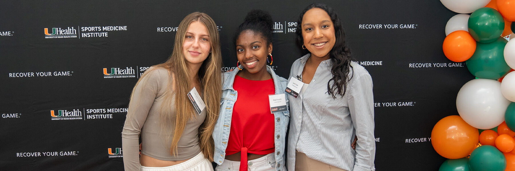 Three young girls standing next to each other while smiling.