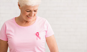 Woman with white hair wearing a pink shirt with a pink ribbon