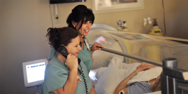 Provider standing next to a hyperbaric medicine chamber